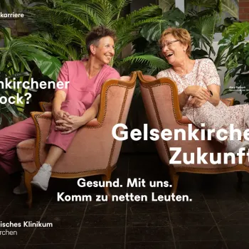 Zwei Personen auf Sesseln lächeln sich an